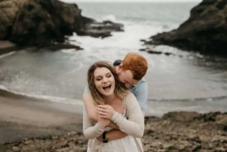 engagement at Piha beach couple laughing