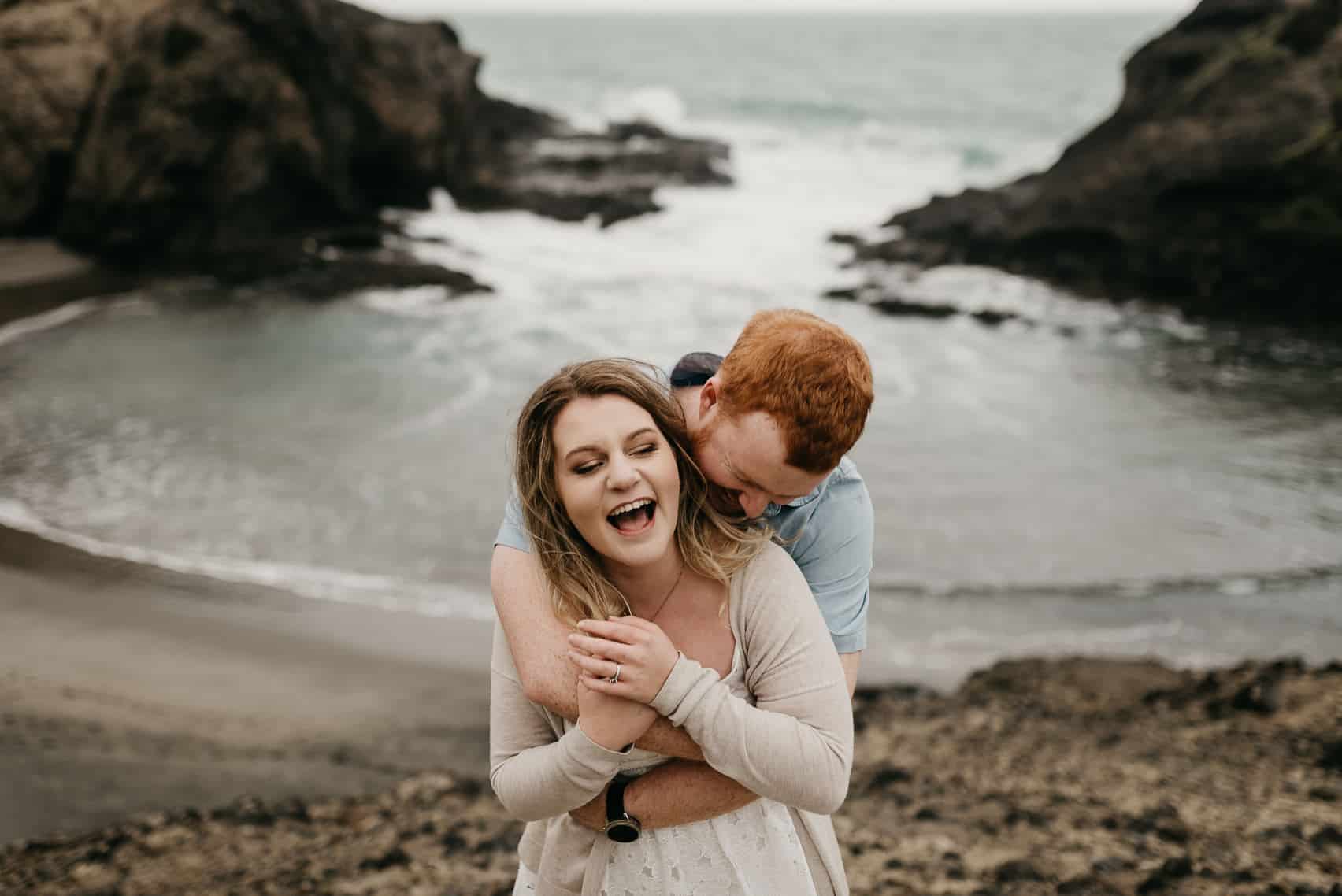 engagement at Piha beach couple laughing